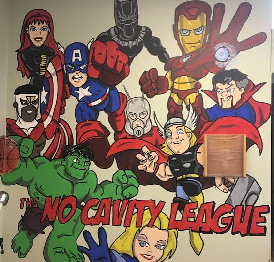 Superhero-themed No Cavity League wall mural in the pediatric dental office